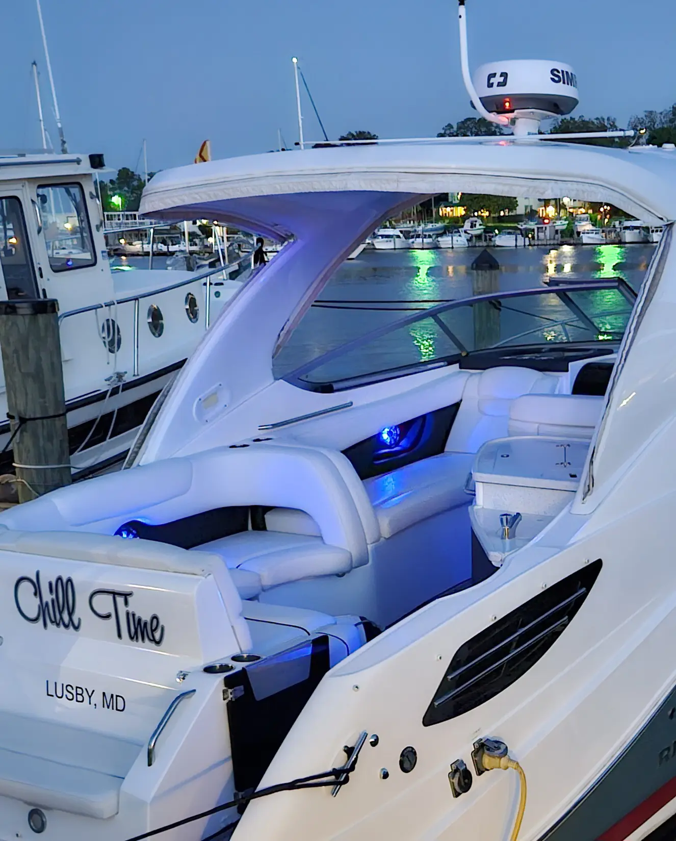Luxurious white yacht docked at a marina during twilight.