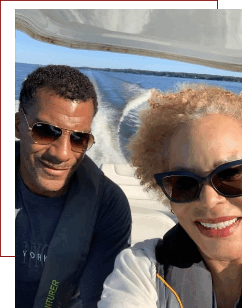Two people wearing sunglasses smiling outdoors on a sunny day.