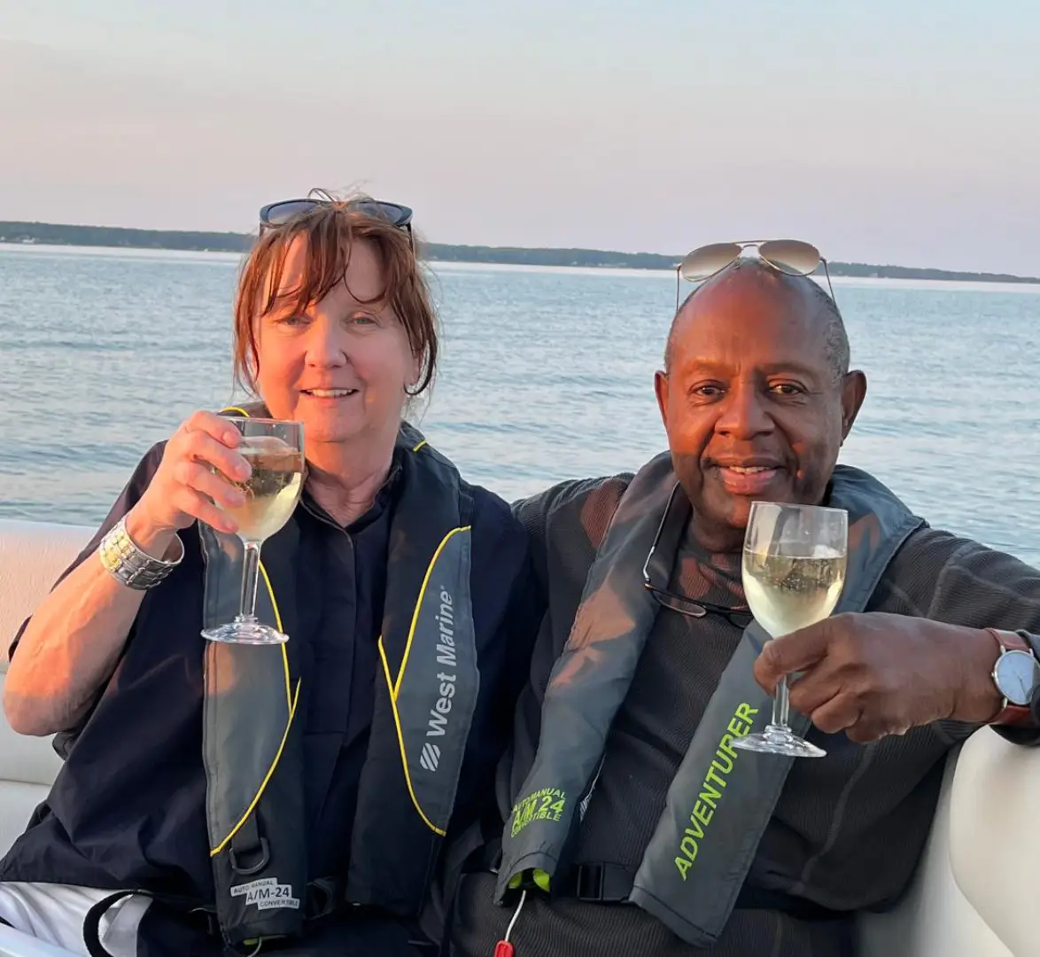 Two people enjoying a drink together by the water at sunset.